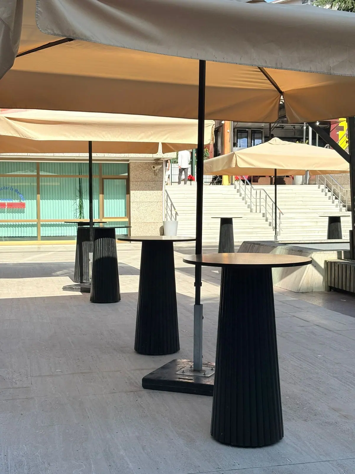 Kurumsal avluda siyah bistro masası ve gölgelik yakın görünümü