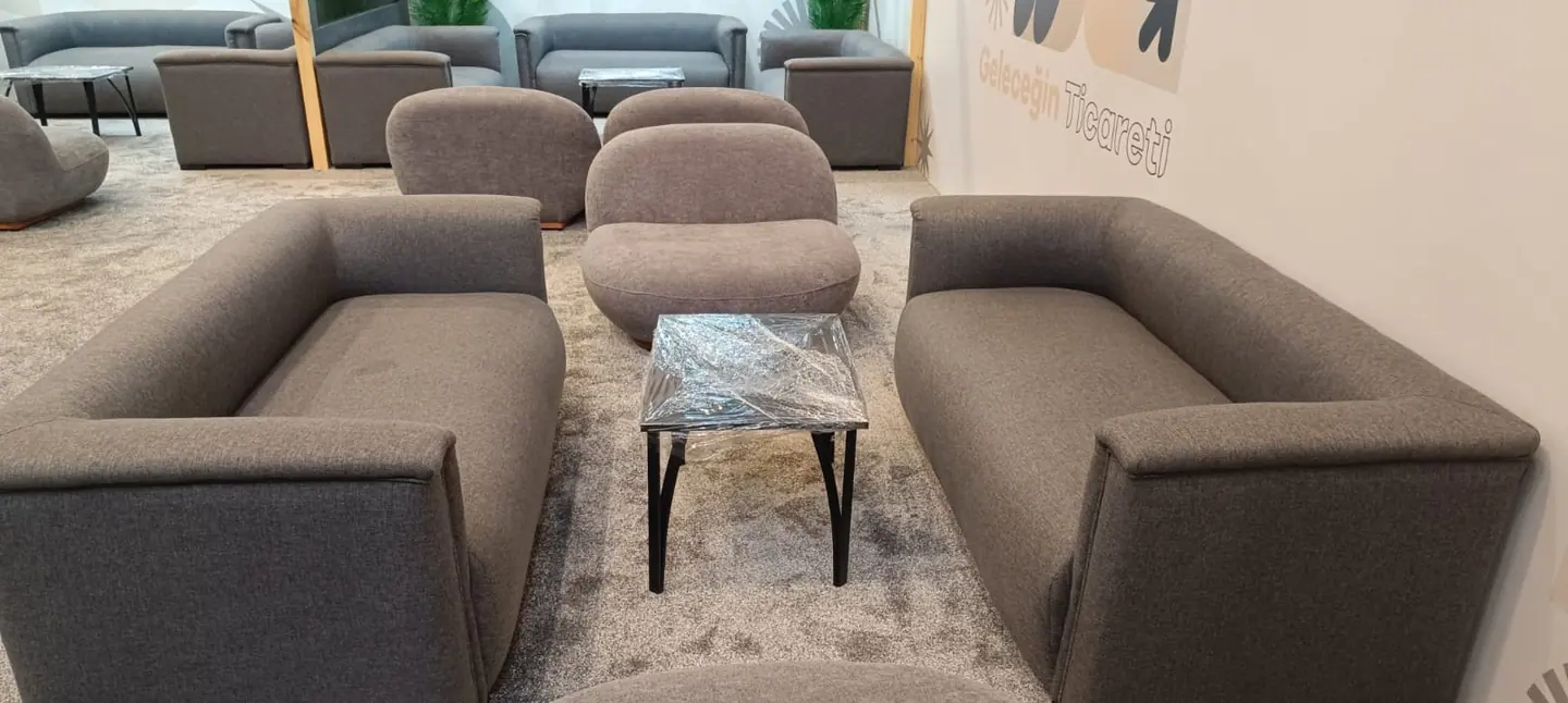Geleceğin Ticareti yazılı duvar önünde koltuk ve sehpalı lounge kurulumu