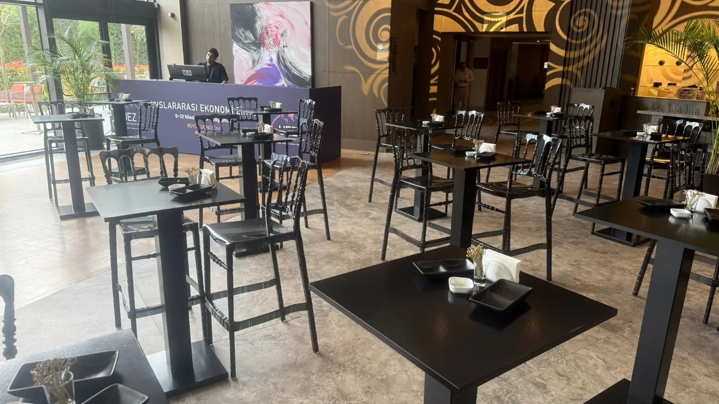 UEZ 2026 salonunda siyah yüksek masa ve sandalyelerle networking yerleşimi